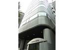 グレーの丸みのある6階建てのビルです。